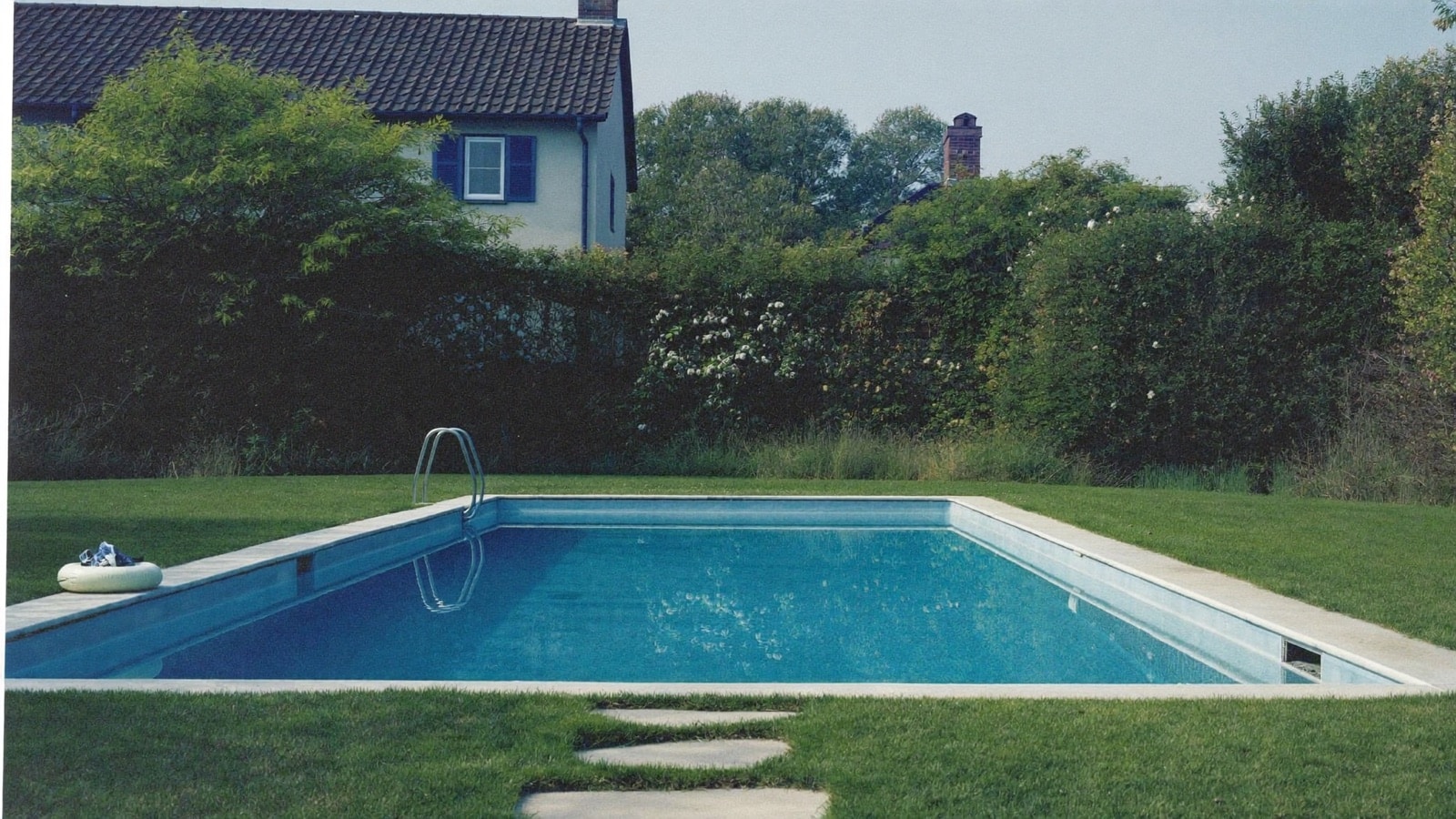 Piscine familiale avec maison en fond au printemps